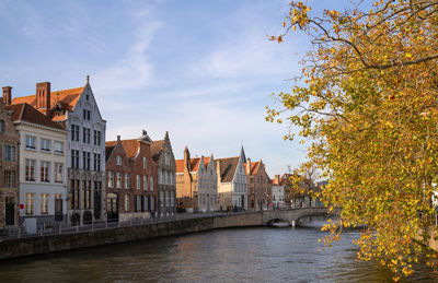 River amidst buildings against sky during autumn