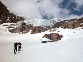 People on snowcapped mountain against sky