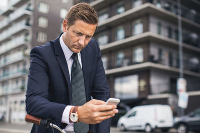 Businessman using smart phone in city