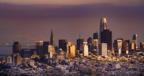 Modern buildings in city against sky during sunset