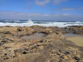 Scenic view of rocks on beach against sky