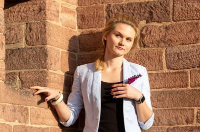 Portrait of young woman standing against wall