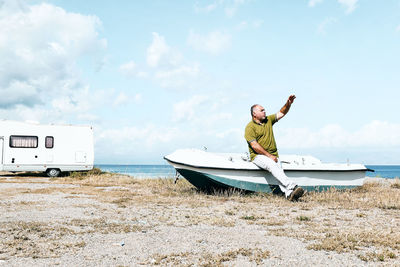 Man standing on boat in sea against sky