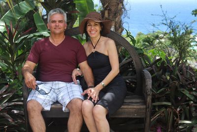 Portrait of happy couple sitting on bench by plants