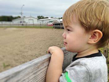 Cute boy looking down while standing by water