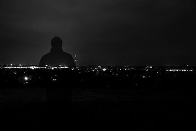 Rear view of silhouette woman against illuminated cityscape