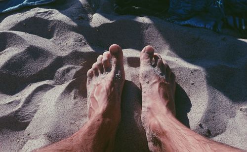 Low section of man sitting on sand