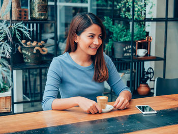 Portrait of smiling young woman with drink on table