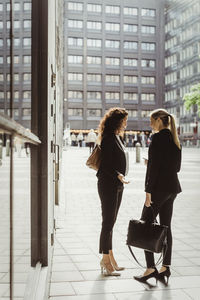 Businesswomen talking while standing by building