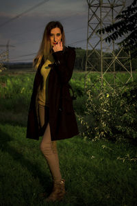 Young woman standing on grass against sky