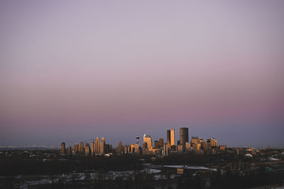 Modern buildings in city against sky during sunset