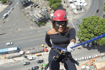 A woman wearing a hero costume with protective helmet walking down a tall rappel building. 