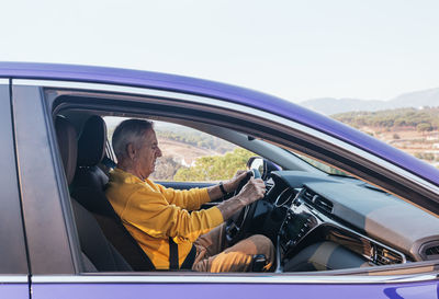 Side view of man sitting in car