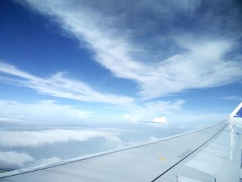 Low angle view of cropped airplane against blue sky