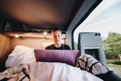 Young woman using laptop in camper