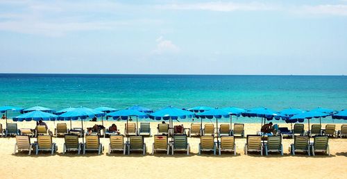 Chairs on beach by sea against sky