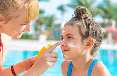 Mother applying suntan lotion on daughters face