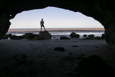 Silhouette rocks on beach against clear sky