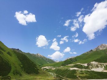 Scenic view of green mountains against sky on sunny day