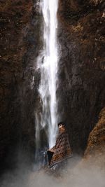 Man standing against waterfall in forest