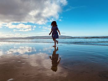 Woman standing on beach against sky