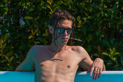 Portrait of young man standing by swimming pool