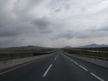 Empty road against cloudy sky
