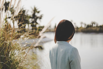 Rear view of woman looking at lake against sky