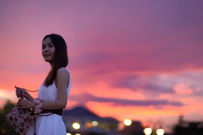 Woman standing against sky during sunset