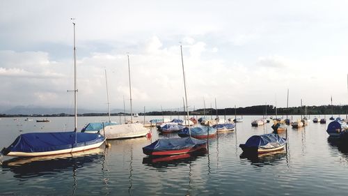 Boats moored at harbor against sky