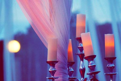 Close-up of illuminated candles on glass table
