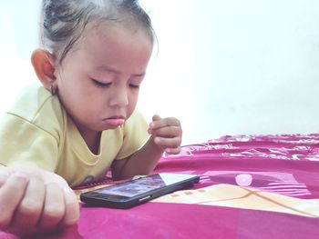 Cute boy using mobile phone on bed