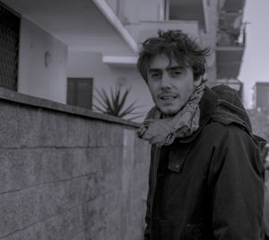 Portrait of young man standing by wall
