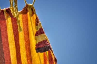 Low angle view of clothes drying against clear blue sky