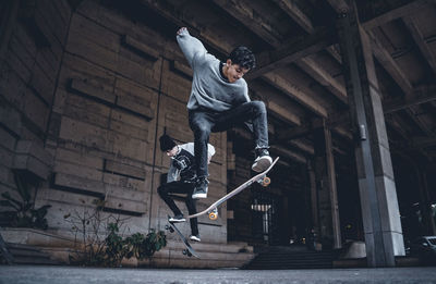 Full length of young man jumping against built structure