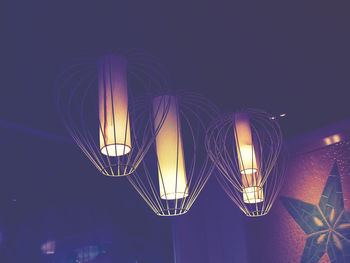 Low angle view of illuminated lighting equipment against sky at night