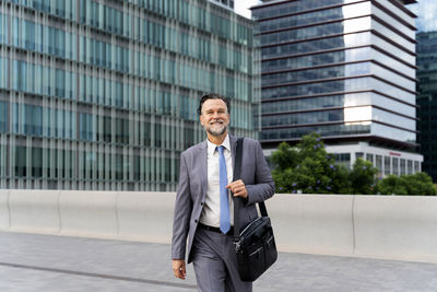 Smiling mature businessman walking on footpath