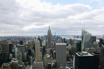 Aerial view of buildings in city against cloudy sky