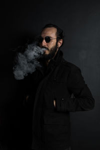 Man smoking cigarette while standing against wall