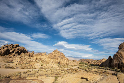 Rock formations on landscape against sky with lenticular clouds