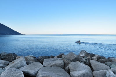 Scenic view of rocks in sea against clear sky