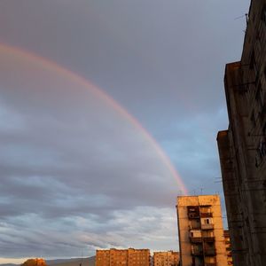 Low angle view of rainbow over buildings against sky