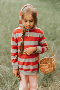 Upset or focused eight year old kid girl mushroom picker is seek for and picking mushrooms