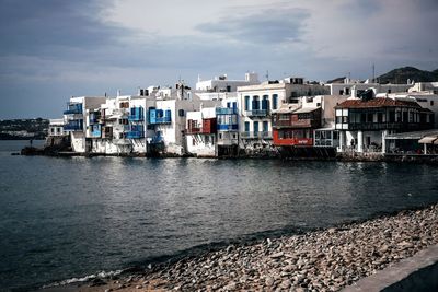 Buildings by sea against sky in city