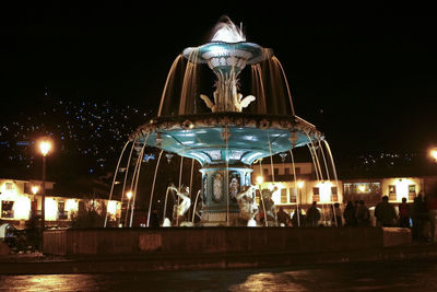 People by illuminated fountain at plaza de armas