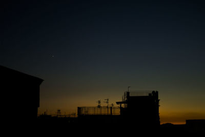 Low angle view of silhouette buildings against clear sky