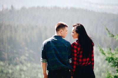 Rear view of young couple standing face to face in forest