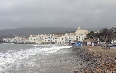 View of beach and buildings against cloudy sky