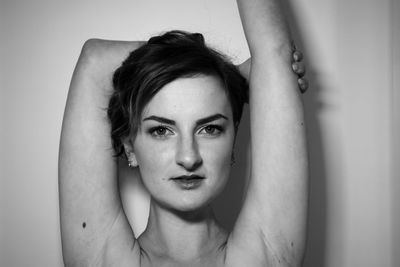 Portrait of young woman standing by wall at home