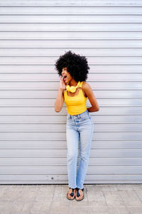 Portrait of young woman standing against wall